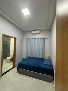 a bedroom with a blue bed and a bathroom at Aluguel na cop30 in Ananindeua
