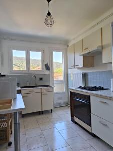 a kitchen with white cabinets and a stove top oven at Appartement 4 pers Balcon Parking gratuit in Amélie-les-Bains-Palalda