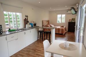 a kitchen with white cabinets and a table and a living room at Cabañas El Nono in Tandil