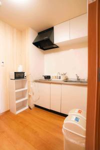 Una cocina con gabinetes blancos, un fregadero y una estufa. en 恩納村真栄田シービュー民宿, en Onna