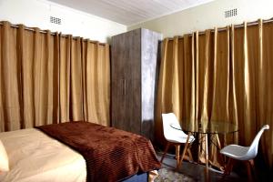 a bedroom with curtains and a bed and a table at Private Guest suite in Ferndale in Johannesburg