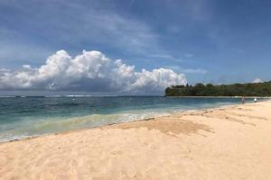 a sandy beach with the ocean and clouds in the sky at Private Room in Villa Near Nusa Dua Beach Bali in Nusa Dua
