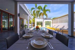 a dining table with plates and wine glasses on a patio at Beautiful 4-Bedroom Pool Villa - BL9 in Hua Hin