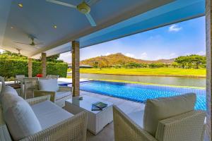 an outdoor patio with a pool and chairs and a view at Nice 3BR with Golf Course View - BMG3 in Hua Hin