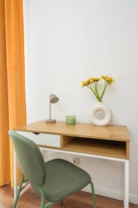 a desk with a green chair and a vase of flowers at Lumina Charming 3-room apartment in the center of Warsaw in Warsaw