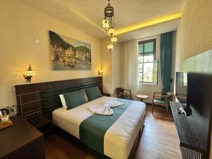 a hotel room with a bed and a flat screen tv at Ottoman Şükrü Efendi Hotel in Ordu