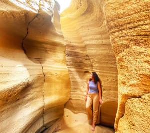 a woman walking through a slot canyon at All-Inclusive Surf Packages and Activity Everyday in Agadir +5 photos