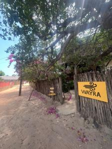 un panneau sur une clôture en bois à côté d'un arbre dans l'établissement Casa Wayra, à Barra Grande