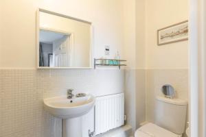 Un baño con lavabo, inodoro y espejo. en About Tern - 10-Minute Walk to Poole Quay, with Harbour Views, en Poole