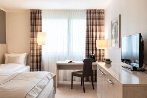 Una habitación de hotel con una cama y un escritorio con televisión. en Garner Hotel Mainz by IHG, en Mainz 82 fotos más
