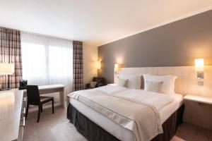 a hotel room with a large bed and a desk at Garner Hotel Mainz by IHG in Mainz