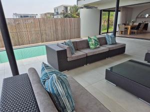 a living room with a couch and pillows on a patio at Modern Luxury Beach Villa in Ballito