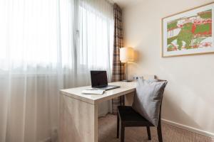 a room with a desk with a laptop computer on it at Garner Hotel Mainz by IHG in Mainz +66 photos