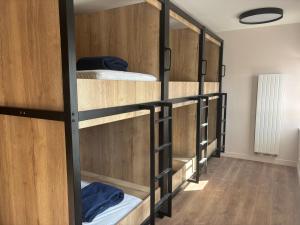 Auberge de Jeunesse Les Francas du Pas-de-Calais - ARRAS في Saint-Laurent-Blangy: صف من الأسرة ذات الطابقين ذات اللون البني في الغرفة