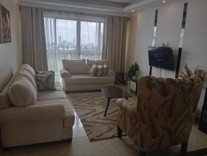 a living room with a couch and chairs and a tv at Blonch's Airbnbs in Nairobi