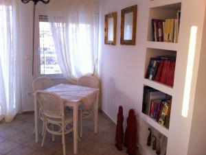 una sala da pranzo con tavolo, sedie e libreria di Family Apartment Ammoudi with shared mini-pool ad Agia Pelagia