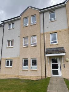 Un edificio de ladrillo con ventanas blancas y una entrada para coches. en travelNess Apartment, en Inverness