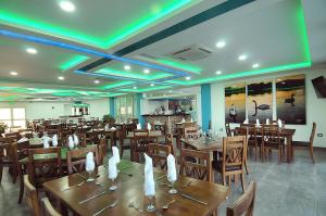 a restaurant with wooden tables and chairs and green lights at Hotel Campestre El Cisne in Barranquilla