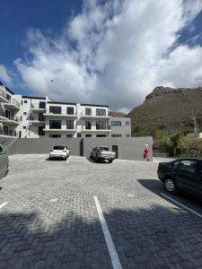 a parking lot with cars parked in front of a building at Marina Views Simon's Town, Near Long Beach in Simonʼs Town