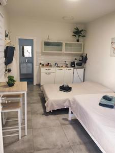 a room with two beds and a table and a kitchen at Dekel Dom Baharava in Beʼer Ora