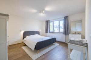 a white bedroom with a bed and a window at Adorable maison 3ch proche de Bruxelles-Tervuren in Tervuren