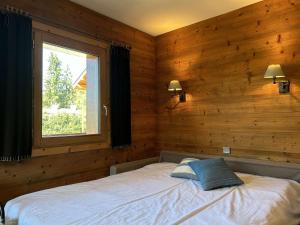 a bedroom with wooden walls and a bed with a window at Studio/Coin montagne - 4 pers, proche pistes & commerces, balcon, parking, WIFI - Méribel - FR-1-180-599 in Les Allues