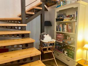 a room with stairs and a book shelf with books at Maison Onze calme en bord de Rance in Plouër-sur-Rance