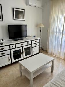 a living room with a tv and a coffee table at Apartamento Pinares del Portil a pie de playa in El Portil