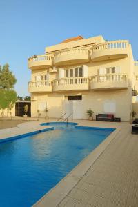 a building with a swimming pool in front of a building at Laguna King - care & comfort in Naj‘ al Aḩwāl