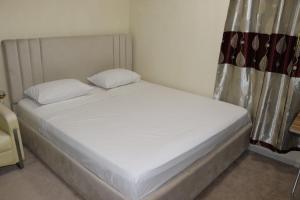 Una cama con sábanas blancas y almohadas en un dormitorio. en Dreams Studio Apartments - Deira, en Dubái