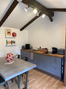 a kitchen with blue cabinets and a table at Charming 2-bed cottage in Peover, Cheshire East in Marthall