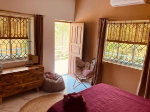 a bedroom with a bed and two windows and a chair at Hidden Haven, Eden in India ! Quietest stay in Goa in Mandrem +61 photos