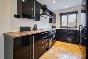 a kitchen with black cabinets and a wooden counter top at Great Ayton Townhouse Retreat-Sleeps 6-3Bed-2Bath in Great Ayton
