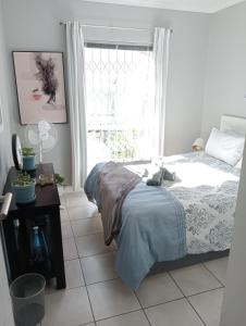 a bedroom with a bed and a window at The Sands Ground-floor apartment in Blouberg in Cape Town