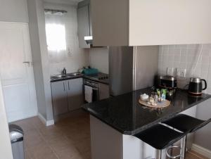 a kitchen with a black counter top in a room at The Sands Ground-floor apartment in Blouberg in Cape Town +6 photos