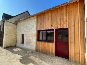 a wooden building with a red door on it at Maison au cœur du pays de Rabelais in Lerné