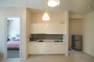 a kitchen with white cabinets and a sink and a bed at Cascades Residency in Kota Damansara in Petaling Jaya