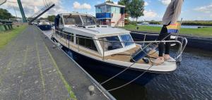 a boat tied up to a dock in the water at Unieke overnachting op een boot in Giethoorn in Giethoorn