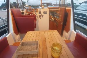 a wooden table on a boat with a wooden floor at Unieke overnachting op een boot in Giethoorn in Giethoorn +2 photos
