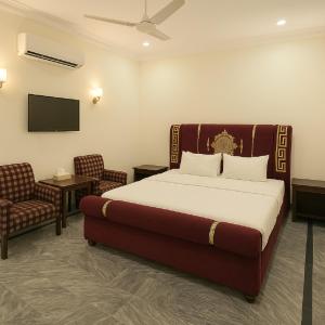 - une chambre avec un lit, une télévision et des chaises dans l'établissement Serenity Lodge Residencia, à Islamabad
