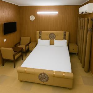 une chambre avec un grand lit et une chaise dans l'établissement Serenity Lodge Residencia, à Islamabad