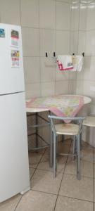 Una mesa y una silla en una cocina con nevera. en Apto familiar no Guarujá, próximo da Praia das Astúrias, en Guarujá