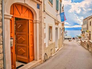 ein Gebäude mit einer orangefarbenen Tür an der Straßenseite in der Unterkunft Apartment & Rooms Antonijela in Bol