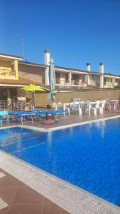 a swimming pool with tables and chairs and an umbrella at TUSCIA RELAx MARE in Civitavecchia