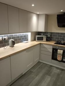 a kitchen with white cabinets and a microwave at Lower Cheltenham Place in Bristol