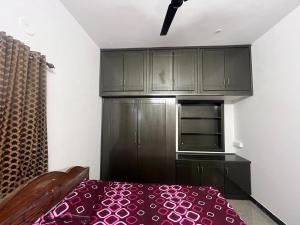 a kitchen with black cabinets and a red bed at Ajith 3bhk premium house in Pollāchi