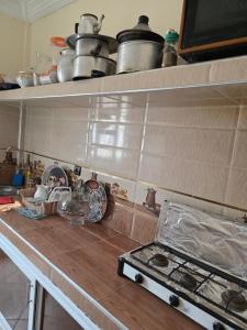 a kitchen counter with pots and pans on shelves at Résidence tarfaya in Tarfaya