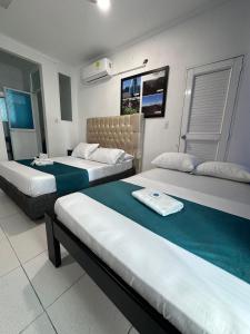 a hotel room with two beds with green sheets at SGH Rodadero Suites in Santa Marta