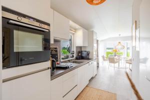a kitchen with white cabinets and a dining room at Strandperle Lathum Ferienhaus in Premium Lage am See für Urlaub und Workation mit Hundestrand in Lathum