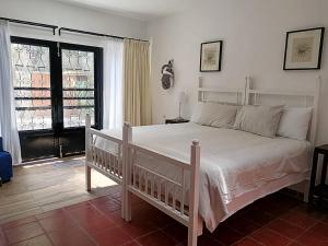 a bedroom with a white bed and a large window at La Casita del Museo in Valladolid